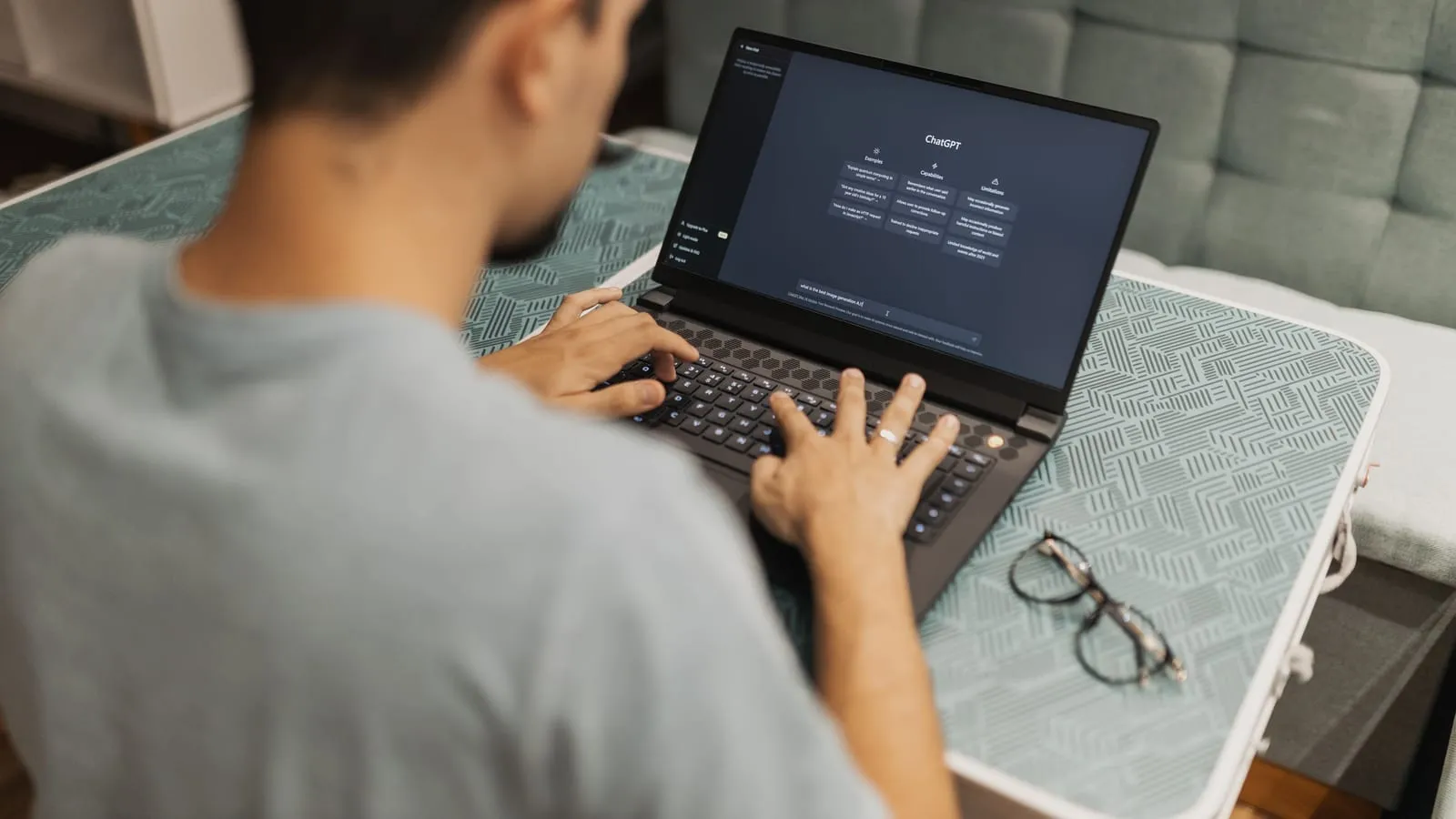 A person typing on a laptop with an AI chat assistant open on screen.